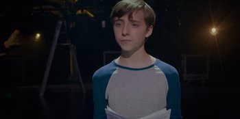 Movie still from “Better Nate Than Ever” (2022), directed by Tim Federle – A young man with a bandaged arm and a blue shirt; Medium shot, Over the shoulder angle