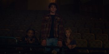 Movie still from “Better Nate Than Ever” (2022), directed by Tim Federle – A man and two women sitting in a movie theater; Medium shot, Low angle