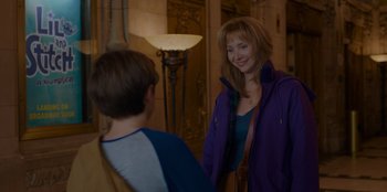 Movie still from “Better Nate Than Ever” (2022), directed by Tim Federle – A woman in a purple jacket standing next to a young boy; Medium shot, Over the shoulder angle