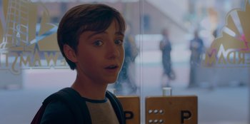 Movie still from “Better Nate Than Ever” (2022), directed by Tim Federle – A young man looking at the camera while standing in front of a window; Close Up shot, Over the shoulder angle