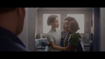 A woman holding a child and a man in a room
