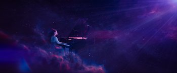 A woman sitting at a grand piano in the middle of the night