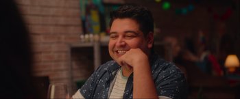 Movie still from “Beyond the Universe” (2022), directed by Diego Freitas – A young man smiling while sitting at a table; Close Up shot, Over the shoulder angle