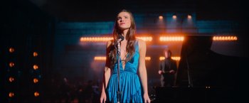 A woman in a blue dress singing into a microphone