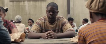 Movie still from “Big George Foreman” (2023), directed by George Tillman Jr. – A man sitting at a table with his hands crossed; Medium shot, Over the shoulder angle