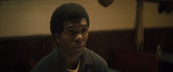 Movie still from “Big George Foreman” (2023), directed by George Tillman Jr. – A person sitting in front of a wall; Close Up shot, Over the shoulder angle