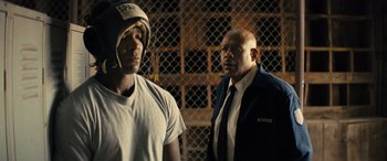 Movie still from “Big George Foreman” (2023), directed by George Tillman Jr. – A man and a man in a suit and helmet; Medium shot, Over the shoulder angle