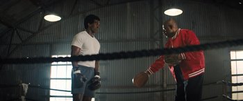 Movie still from “Big George Foreman” (2023), directed by George Tillman Jr. – Two men are boxing in an indoor boxing ring; Medium shot, Low angle