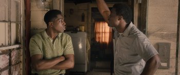 Movie still from “Big George Foreman” (2023), directed by George Tillman Jr. – Two men are having a conversation in a kitchen; Medium shot, Over the shoulder angle