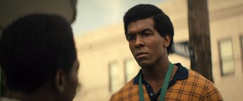 Movie still from “Big George Foreman” (2023), directed by George Tillman Jr. – A young man is standing in front of a building; Close Up shot, Over the shoulder angle