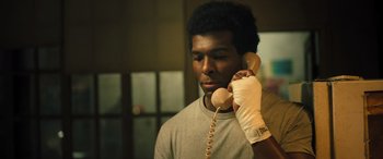 Movie still from “Big George Foreman” (2023), directed by George Tillman Jr. – A man holding a phone up to his ear while wearing gloves; Close Up shot, Low angle