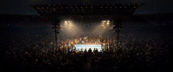 Movie still from “Big George Foreman” (2023), directed by George Tillman Jr. – A crowd of people watching a boxing match in a boxing ring; Extreme Wide shot, High angle