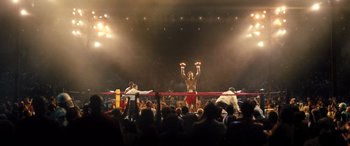 Movie still from “Big George Foreman” (2023), directed by George Tillman Jr. – A boxing ring filled with people in the middle of a fight; Extreme Wide shot, Low angle
