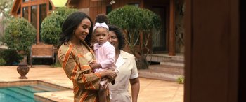 Movie still from “Big George Foreman” (2023), directed by George Tillman Jr. – Two women and a child standing in front of a house; Medium shot, Over the shoulder angle