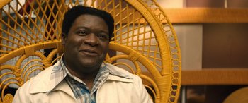 Movie still from “Big George Foreman” (2023), directed by George Tillman Jr. – A person sitting in a chair; Close Up shot, High angle