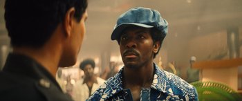 Movie still from “Big George Foreman” (2023), directed by George Tillman Jr. – A man wearing a blue hat talking to another man in a crowd; Close Up shot, Over the shoulder angle
