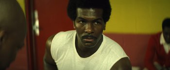 Movie still from “Big George Foreman” (2023), directed by George Tillman Jr. – A person wearing a white t - shirt; Close Up shot, Low angle