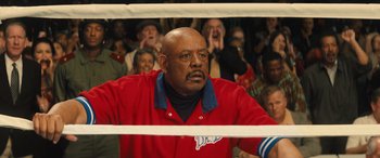 Movie still from “Big George Foreman” (2023), directed by George Tillman Jr. – A man in a boxing ring wearing a red jacket; Close Up shot, High angle