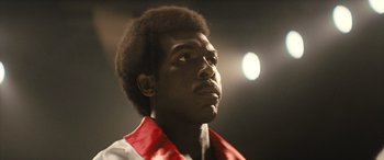 Movie still from “Big George Foreman” (2023), directed by George Tillman Jr. – A person wearing a red and white shirt; Close Up shot, Low angle