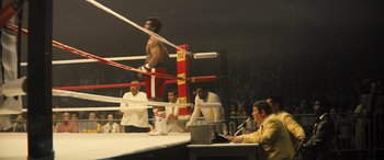 Movie still from “Big George Foreman” (2023), directed by George Tillman Jr. – A man standing in a boxing ring in front of a crowd; Wide shot, Low angle