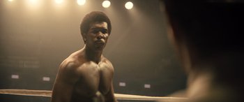 Movie still from “Big George Foreman” (2023), directed by George Tillman Jr. – A man in a boxing ring with his hands in his pockets; Close Up shot, Low angle