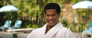 Movie still from “Big George Foreman” (2023), directed by George Tillman Jr. – A man in a white robe smiling for the camera; Close Up shot, High angle