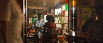 Movie still from “Big George Foreman” (2023), directed by George Tillman Jr. – A man and a woman are sitting at a table; Wide shot, Low angle