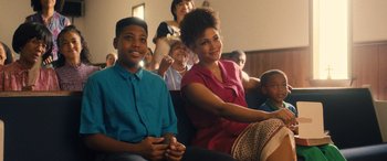 Movie still from “Big George Foreman” (2023), directed by George Tillman Jr. – A woman and a boy are sitting in a room; Medium shot, Over the shoulder angle