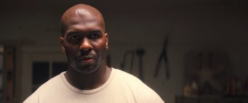 Movie still from “Big George Foreman” (2023), directed by George Tillman Jr. – A man with a bald head is standing in front of a wall; Close Up shot, Low angle