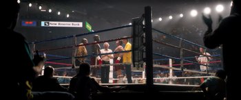 Movie still from “Big George Foreman” (2023), directed by George Tillman Jr. – A group of men standing in a boxing ring; Extreme Wide shot, High angle