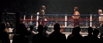 Movie still from “Big George Foreman” (2023), directed by George Tillman Jr. – A man in a boxing ring with people in the stands watching; Wide shot, High angle