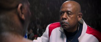 Movie still from “Big George Foreman” (2023), directed by George Tillman Jr. – An older man sitting in front of an audience; Close Up shot, Low angle