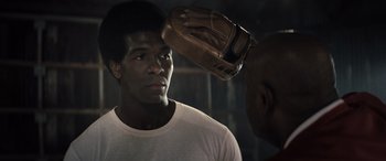 Movie still from “Big George Foreman” (2023), directed by George Tillman Jr. – A man with a baseball glove on his head; Close Up shot, Over the shoulder angle