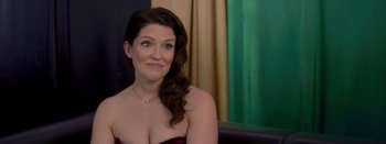 Movie still from “Big Gold Brick” (2022), directed by Brian Petsos – A woman sitting in front of a green curtain; Close Up shot, Over the shoulder angle