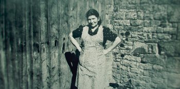 An old photo of a woman standing in front of a brick wall