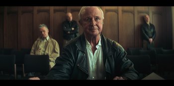 An older man wearing a leather jacket in a room