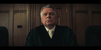 An older man wearing a black robe and a white tie