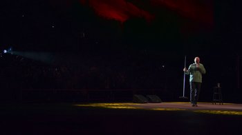 Movie still from “Bill Burr: Live at Red Rocks” (2022), directed by Mike Binder – A person standing on a stage with a microphone; Extreme Wide shot, High angle