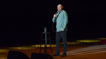 Movie still from “Bill Burr: Live at Red Rocks” (2022), directed by Mike Binder – A man standing on a stage holding a microphone; Wide shot, High angle