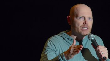 Movie still from “Bill Burr: Live at Red Rocks” (2022), directed by Mike Binder – A bald man wearing a blue shirt and a neck tie; Close Up shot, Over the shoulder angle