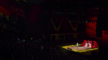 Movie still from “Bill Burr: Live at Red Rocks” (2022), directed by Mike Binder – A crowd of people watching a man on a stage; Extreme Wide shot, High angle