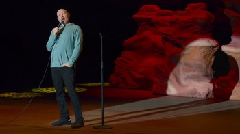 Movie still from “Bill Burr: Live at Red Rocks” (2022), directed by Mike Binder – A man standing on a stage holding a microphone; Wide shot, High angle