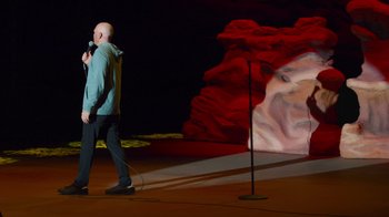 Movie still from “Bill Burr: Live at Red Rocks” (2022), directed by Mike Binder – A man standing on a stage holding a microphone; Extreme Wide shot, High angle