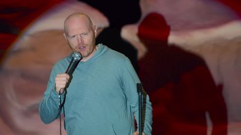 Movie still from “Bill Burr: Live at Red Rocks” (2022), directed by Mike Binder – A man with a shaved head is holding a microphone; Medium shot, High angle