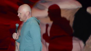 Movie still from “Bill Burr: Live at Red Rocks” (2022), directed by Mike Binder – A bald man standing in front of a microphone; Medium shot, Over the shoulder angle