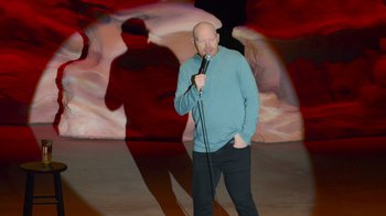 Movie still from “Bill Burr: Live at Red Rocks” (2022), directed by Mike Binder – A man standing in front of a microphone on a stage; Wide shot, High angle