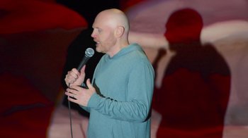 Movie still from “Bill Burr: Live at Red Rocks” (2022), directed by Mike Binder – A bald man is holding a microphone in his hand; Medium shot, Low angle