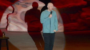 Movie still from “Bill Burr: Live at Red Rocks” (2022), directed by Mike Binder – A man standing on a stage holding a microphone; Wide shot, High angle