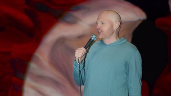 Movie still from “Bill Burr: Live at Red Rocks” (2022), directed by Mike Binder – A man with a bald head is holding a microphone; Medium shot, Low angle