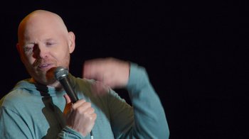Movie still from “Bill Burr: Live at Red Rocks” (2022), directed by Mike Binder – A man holding a microphone in front of a black background; Close Up shot, Over the shoulder angle